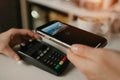 A girl paying for latte with a smartphone by contactless PAY PASS technology