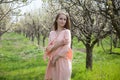 Girl in peach dress walks by a blooming garden Royalty Free Stock Photo