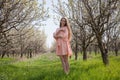 Girl in peach dress walks by a blooming garden Royalty Free Stock Photo