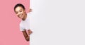 Girl Peeking Out Of Blank Poster Standing Over Pink Background Royalty Free Stock Photo