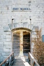 Girl peeks out from behind the ajar wooden door of Mamula Fort