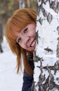 The girl peeks out from behind the birch.