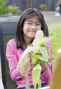 Girl peeling husk off corn cob