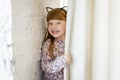 Girl peeping out from behind the curtains with a smile. A little girl with different emotions on her face