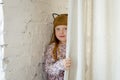 Girl peeping out from behind the curtains with a smile. A little girl with different emotions on her face