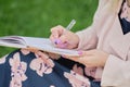 girl with pen writing on notebook on grass outside. Royalty Free Stock Photo