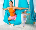 Girl performing butterfly pose holding hanging hammock with hands like wings