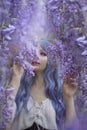 Girl in petals. A beautiful young girl stands in purple petals in a long dress. Glamor. Hair is purple