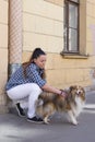 Girl petting the dog shelty on the street Royalty Free Stock Photo