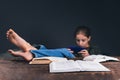 A girl with a phone in her hands. The girl plays on the phone, ignoring books and studies. Open books on the table Royalty Free Stock Photo