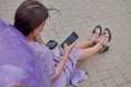 a girl with a phone is sitting by the car in a beautiful dress