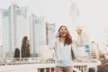 Girl on phone throwing papers in air outdoors.