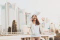 Girl on phone throwing papers in air outdoors.