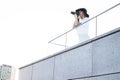 Girl photographer, photographs the city on the roof of the house, a woman tourist looks from the balcony of the hotel at sunset