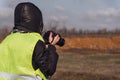 Girl photographer in a yellow rescue vest with a camera in her hands. Back view, no face, copy space Royalty Free Stock Photo