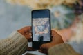 Girl photographing on phone rustic halloween street decor, hands close up. Young woman taking photo of pumpkins and autumn flowers Royalty Free Stock Photo