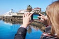 Girl photographs on mobile phone seashore and pier