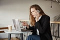 Girl picking item in online-store. Indoor shot of good-looking female student in cafe, sitting over laptop, pointing at