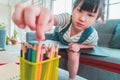Girl picking up colorful crayon pencil on the table for creative drawing at home, for Creative education concept Royalty Free Stock Photo