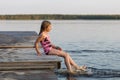 The girl on the pier splashes by his feet in the lake