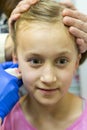 Girl pierced ear in the beauty salon. Adorable little girl having ear piercing process with special equipment in beauty center by Royalty Free Stock Photo