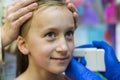 Girl pierced ear in the beauty salon. Adorable little girl having ear piercing process with special equipment in beauty center by