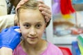 Girl pierced ear in the beauty salon. Adorable little girl having ear piercing process with special equipment in beauty center by