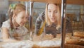 Girl with a pigtail and her mom look at the pies in the window choosing Royalty Free Stock Photo