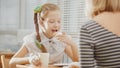 Girl with pigtails eats cakes with her mum in the cafe Royalty Free Stock Photo
