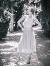 A girl with pigtails in a light tulle skirt and high-heeled shoes stands in a pose on an alley in the park. Black and Royalty Free Stock Photo