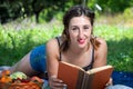 Girl with pigtails reads a book lying on the grass, during a picnic in the park Royalty Free Stock Photo