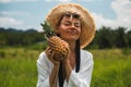 Girl with a pineapple in hand, in a white dress