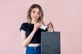 a girl on a pink background with a black paper bag. shopping concept, bank or discount card mockup