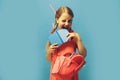 Girl with pink bag bites notebook. Kid with naughty face Royalty Free Stock Photo