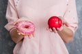 A girl in a pink blouse holding a doughnut and a red Apple Royalty Free Stock Photo