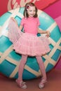 Girl in pink clothes with a Lollipop. In the background, a variety of sweets.