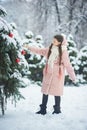 Girl in pink coat in snow Park. Girl plays in winter Park. Adorable child walking in snow winter forest Royalty Free Stock Photo