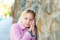 A girl in a pink coat stands near the wall, rubbing close-ups. Royalty Free Stock Photo