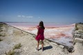 Girl in pink dress against red salt lake in Saline Margherita di Savoia of Italy Royalty Free Stock Photo