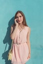 Girl in pink dress, in background summer wall, makes phone calls, listens to voice message in Internet application, a Royalty Free Stock Photo