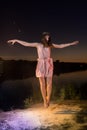 Girl in pink dress jumping on the river beach during sunset and white flour on the ground Royalty Free Stock Photo