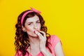 Girl in pink dress pinup-style eats cream licks fingers Royalty Free Stock Photo