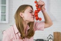 Girl in a pink dress sniffs a sprig of red cherry tomato. Royalty Free Stock Photo