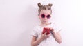 A girl in pink glasses uses a red smartphone.