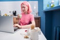 Girl with pink hair drinking her morning matcha tea and working at her laptop Royalty Free Stock Photo