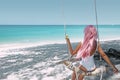 Girl with pink hair hanging on swing at beach Royalty Free Stock Photo