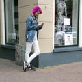 Girl with pink hair leans against store with fashion for women w