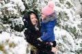 A girl in a pink hat hugs her mother against the background of trees in the snow Royalty Free Stock Photo