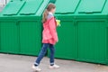 A girl in a pink jacket, carrying disposable glasses in a dumpster to throw them away Royalty Free Stock Photo