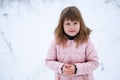 Girl in pink jacket gently freezing outside in winter, snow, em